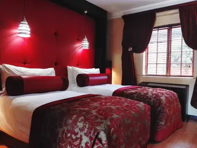 a hotel room with two beds with red walls at Cycad Guest House in Polokwane
