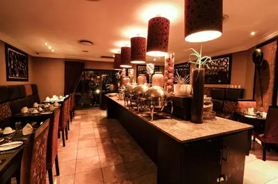 a restaurant with a long bar with tables and chairs at Cycad Guest House in Polokwane