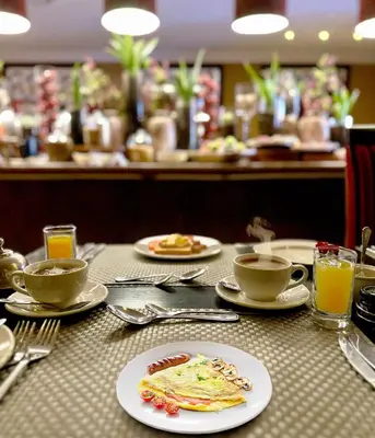 a table with plates of food and cups of coffee at Cycad Guest House in Polokwane