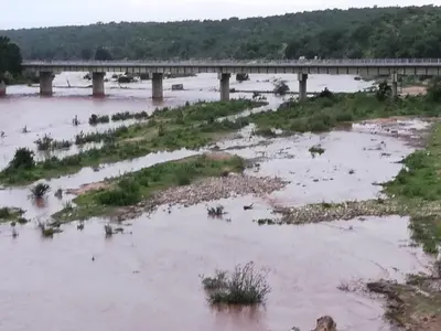 a river with a bridge in the background at Three Bridges B&B in Hoedspruit