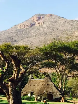a house with a thatched roof in front of a mountain at Ithaba Falls Guest Farm Farm L59, Buffelsvley, Burgersfort, 1150 in Boerboomskraal