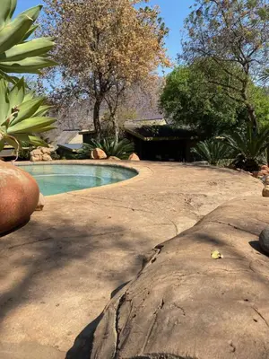 a swimming pool in a yard with a large rock at Ithaba Falls Guest Farm Farm L59, Buffelsvley, Burgersfort, 1150 in Boerboomskraal