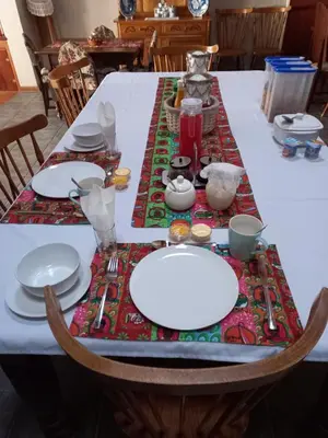 a table with white plates and utensils on it at De Zevende Hemel Guesthouse in Secunda