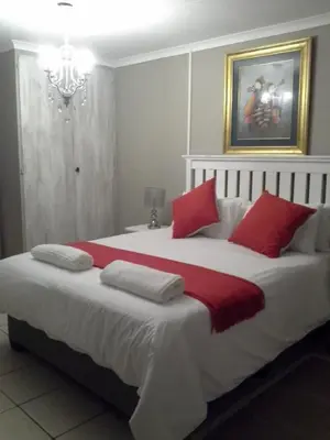a bedroom with a large bed with red pillows at De Zevende Hemel Guesthouse in Secunda