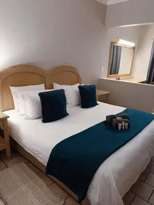 a bedroom with a large white bed with blue pillows at Pecan Farm Guesthouse in Louis Trichardt