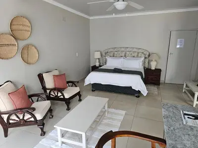 a bedroom with a bed and two chairs and a table at Pecan Farm Guesthouse in Louis Trichardt