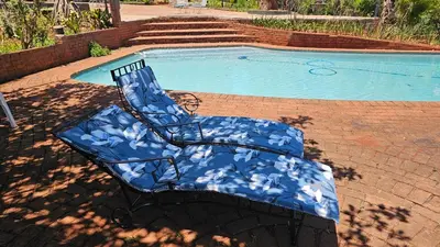 a blue chair sitting next to a swimming pool at Pecan Farm Guesthouse in Louis Trichardt