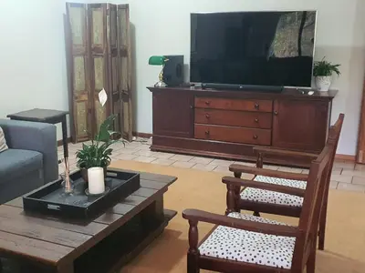 a living room with a tv and a table and chairs at Pecan Farm Guesthouse in Louis Trichardt