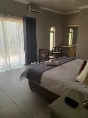 a bedroom with two beds and a table and window at Pecan Farm Guesthouse in Louis Trichardt