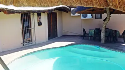 a swimming pool with an umbrella and a house at Lani's Guest House - No Loadshedding in Musina