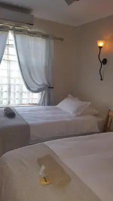 two beds in a hotel room with a window at Lani's Guest House - No Loadshedding in Musina