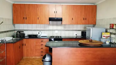 a kitchen with wooden cabinets and a counter top at Lani's Guest House - No Loadshedding in Musina