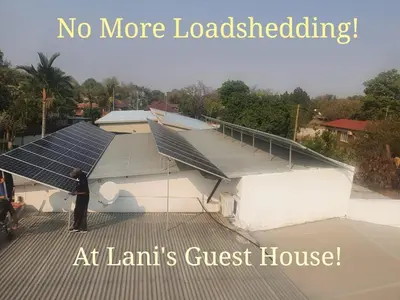 a man standing on the roof of a building with solar panels at Lani's Guest House - No Loadshedding in Musina