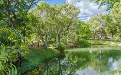 a river in a park with trees and grass at LittleBush Private Lodge in Hoedspruit