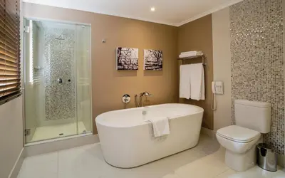a bathroom with a tub and a toilet and a shower at The Centurion Hotel in Centurion