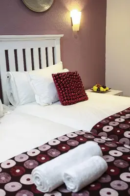 a hotel room with a bed with towels on it at Woodlands Guest House in Hazyview