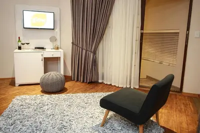 a living room with a black chair and a television at Woodlands Guest House in Hazyview