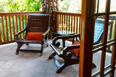 a rocking chair and a table on a porch at Woodlands Guest House in Hazyview