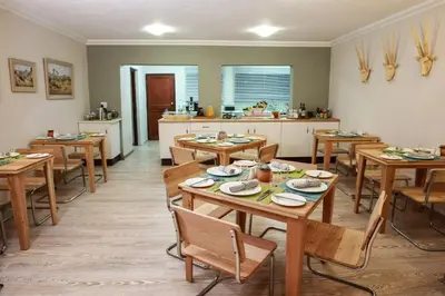 a dining room with wooden tables and a kitchen at Woodlands Guest House in Hazyview