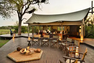 a deck with a tent and tables and chairs at Rhino Walking Safaris in Skukuza