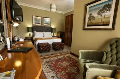 a hotel room with a bed and a table at Mavuta Manor in Polokwane