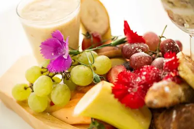 a plate of food with grapes and fruit and a drink at Mavuta Manor in Polokwane