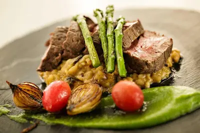 a plate of food with meat and beans and asparagus at Mavuta Manor in Polokwane