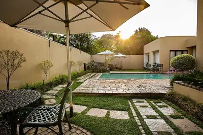 a patio with an umbrella and a swimming pool at Mavuta Manor in Polokwane