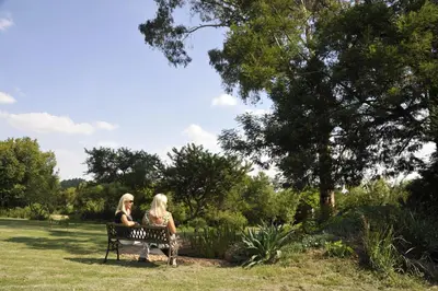 two women sitting on a bench in a park at Ipe Tombe Guest Lodge - Midrand in Midrand