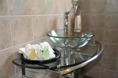 a glass bowl and toothbrushes on a glass shelf next to a sink at Ipe Tombe Guest Lodge - Midrand in Midrand