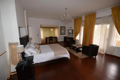a bedroom with a large bed and a living room at Attaché Guest Lodge & Health Spa in Midrand