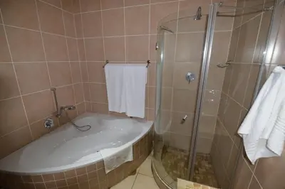 a bathroom with a shower and a bath tub at Attaché Guest Lodge & Health Spa in Midrand