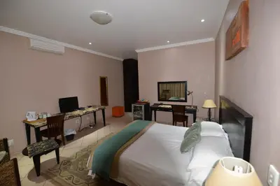 a bedroom with a bed and a desk with a computer at Attaché Guest Lodge & Health Spa in Midrand