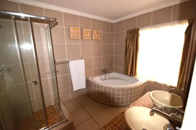 a bathroom with a shower and a tub and a sink at Attaché Guest Lodge & Health Spa in Midrand