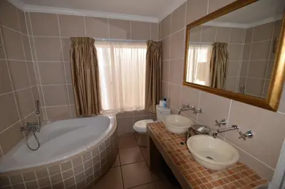 a bathroom with a tub and a sink and a toilet at Attaché Guest Lodge & Health Spa in Midrand