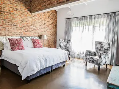 a bedroom with a bed and a brick wall at Rustique Boutique Hotel in Middelburg
