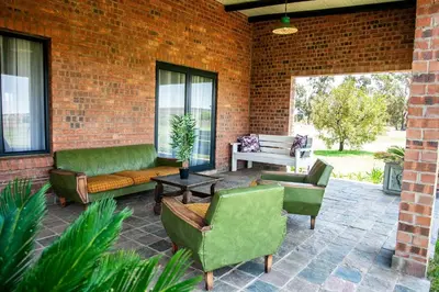 a patio with green furniture and a brick wall at Rustique Boutique Hotel in Middelburg