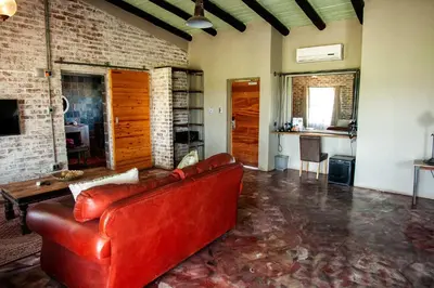 a living room with a red couch and a kitchen at Rustique Boutique Hotel in Middelburg