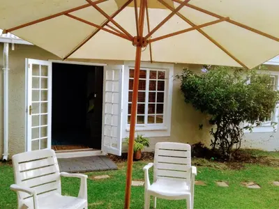 two chairs and an umbrella in front of a house at Limonite GuestHouse in Pretoria