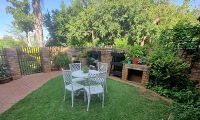 a patio with a table and chairs on the grass at Big Boma Guest House in Lydenburg