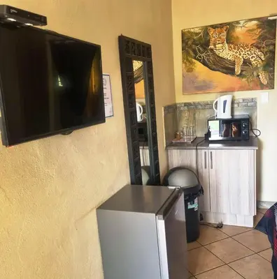 a room with a television on a wall with a refrigerator at Big Boma Guest House in Lydenburg