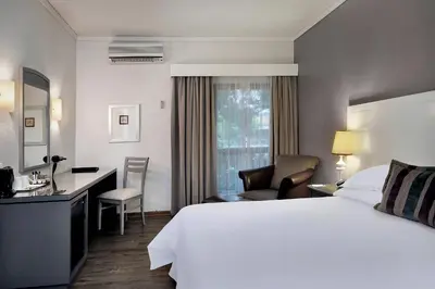 a hotel room with a large bed and a desk at Protea Hotel by Marriott Midrand in Midrand