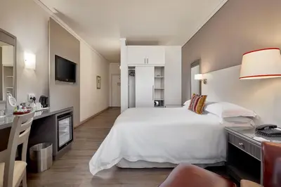 a bedroom with a large white bed and a desk at Protea Hotel by Marriott Midrand in Midrand