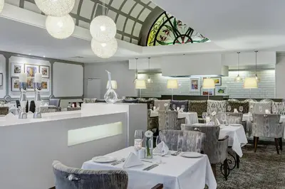 a restaurant with white tables and chairs and a window at Protea Hotel by Marriott Midrand in Midrand