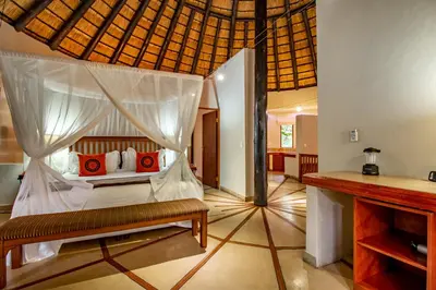 a bedroom with a canopy bed with red pillows at Blue Jay Lodge in Hazyview