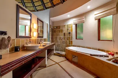 a large bathroom with a tub and two sinks at Blue Jay Lodge in Hazyview