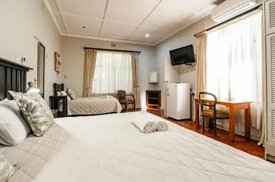 a bedroom with a large white bed with shoes on it at The Village in Hatfield in Pretoria