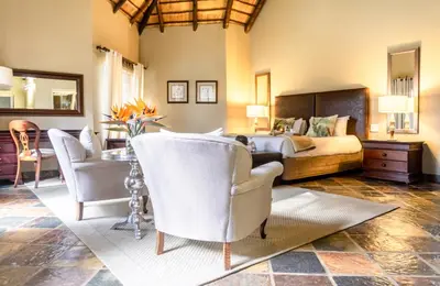 a bedroom with a bed and a table and chairs at Re a Lora Lodge in Bela-Bela