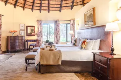 a bedroom with a large bed and a table and chairs at Re a Lora Lodge in Bela-Bela