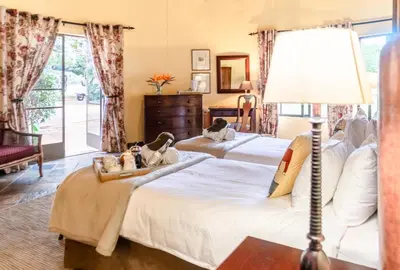 a bedroom with two beds and a lamp at Re a Lora Lodge in Bela-Bela